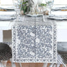 Dining room with white table and chairs, floral centerpiece, and decorative plates on the wall.