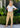 Woman wearing a white top and yellow floral pants standing outdoors.