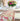 Dining table set with a floral tablecloth, plates, glasses, and a vase of flowers.